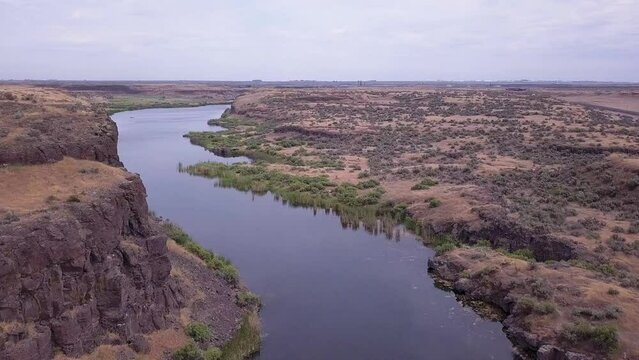 Western sagebrush flyover of Scablands pond to kayakers in distance