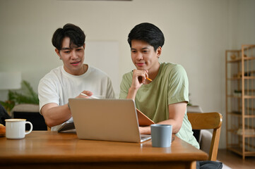 Obraz premium A smart Asian male college student is studying an online lesson at home together.