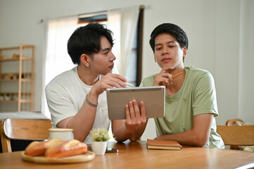 A handsome young Asian male gay couple is studying an online lesson at home together