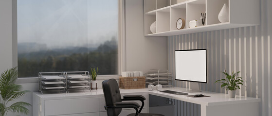 A modern white office workspace with a computer mockup on a white corner table.