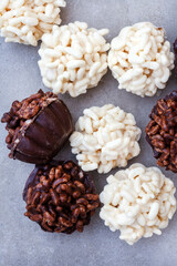 Puffed rice and chocolate cups. Milk and white chocolate crispy rice treats on mottled grey
