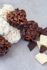 Puffed rice and chocolate cups. Milk and white chocolate crispy rice treats on mottled grey