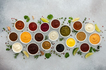 Different types of sauces in bowls with seasonings, rosemary and pepper, thyme and garlic, lime and lemon, cilantro, top view, copy space