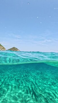Over-Under Split Shot of Turquoise Underwater Ocean Seascape at Beautiful Beach with Landscape Above at Costa Rei, Sardinia, Italy, Vertical Video