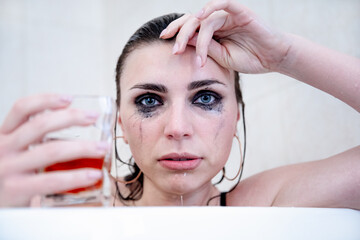 Naklejka premium Young beautiful brunette with blue eyes, heavily flowing makeup and a glass glass in her hand.