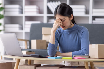 Young asian woman ecommerce SME business stressed leaning on package at home office, stressed...
