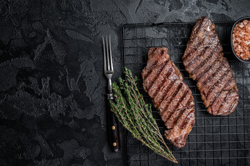 Grilled denver beef meat steak on a rack. Black background. Top view. Copy space