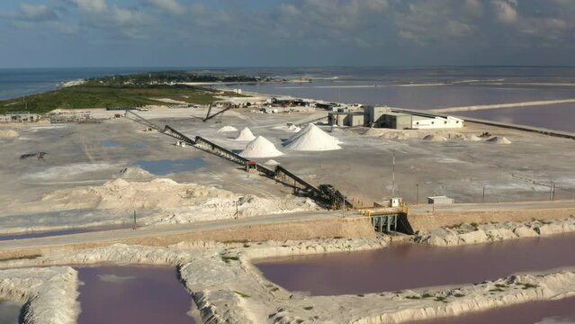 Sea saltern in Mexico with mounds of salt and salt evaporation ponds.
