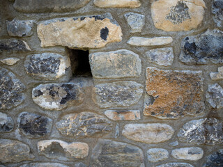imagen detalle pared de piedras de distintos tamaños con las juntas de cemento y un agujero 