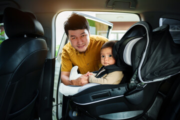 father take care his infant baby in car seat.