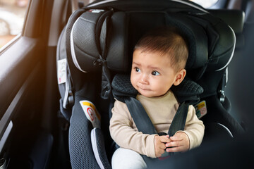 happy infant baby sitting in car seat and looking out of window, safety chair travelling