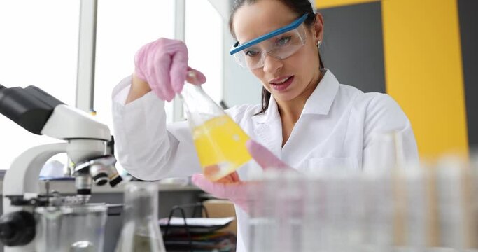 Scientist mixes organic oil in flask in laboratory. Lubricants oil or cosmetic products concept