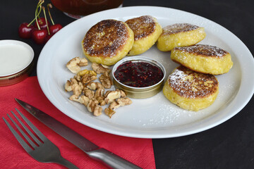 a white plate with cheese pancakes stands on a black table