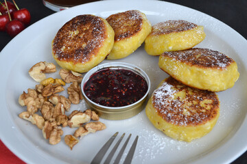 Next to the cheese pancakes are walnuts, jam and cherries