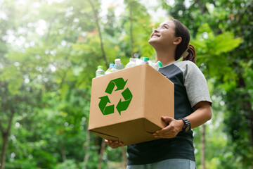 woman holding a garbage box recycling concept Recycle, recycle, plastic-free, junk food plastic packaging. on a forest nature green background - obrazy, fototapety, plakaty