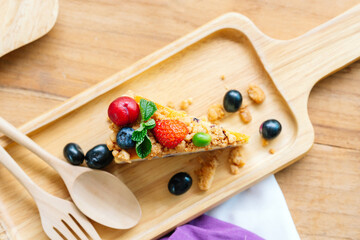 Sliced berry cheesecake served on a wooden plate.
