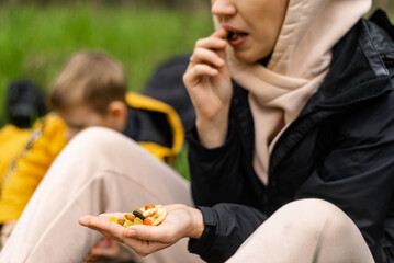 A woman holds various dried fruits and nuts in her hand. Sits on the green grass in the forest....