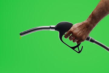 A man's hand holding a fuel pump nozzle at green-screen background. Petrol drop