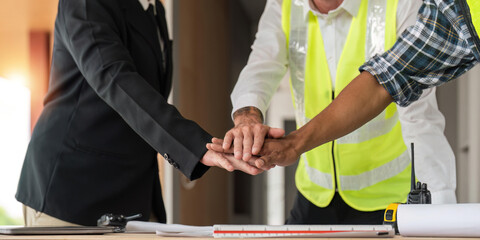 Construction workers, architects and engineers shake hands after completing an agreement in an office facility, successful cooperation concept