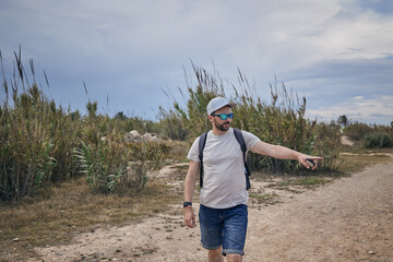 A young man with a backpack walks along a country road