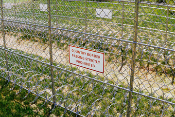Country border sign. Passing is strictly prohibited. Boundary fence. Migration