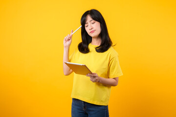 Experience range of emotions with portrait. A young Asian woman wearing yellow t-shirt and denim jeans showcases doubtful expression while using tablet. diverse emotions and technology usage concept.