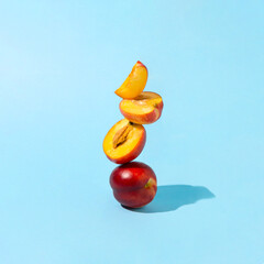 Creative scene nectarine slices lined up on a sunny day. Summer arrangement of red fruits on blue background.