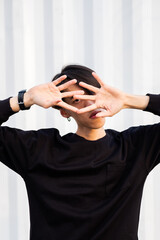 Fototapeta premium Close up portrait of extravagant asian man wearing casual clothes, posing near the wall on the street, urban lifestyle, emotional unusual 