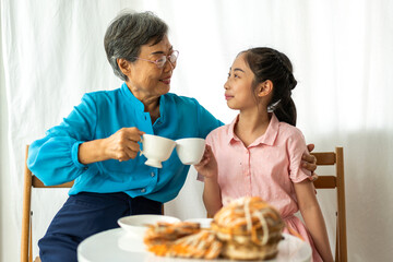 Portrait of happy love asian grandmother and asian little cute girl play and enjoy relax on bed at home.senior, insurance, care.Young girl with their laughing grandparents smiling together.Family