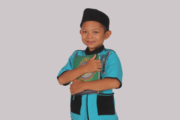 Asian boy smiling holding the Koran and tasbih using koko clothes