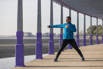 Latino runner stretching in a pergola in a public park.