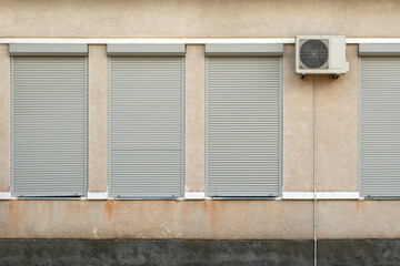 Industrial house facade with air conditioner and metal blinds on windows