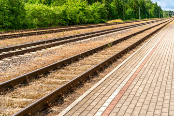 Fototapeta na wymiar Railway platform with paving stones and empty tracks