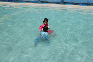 boys and girls practice swimming and playing in water
