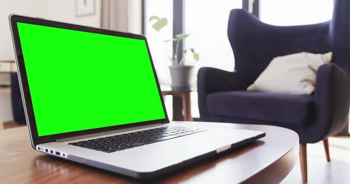 Composition of laptop with green screen on table at home