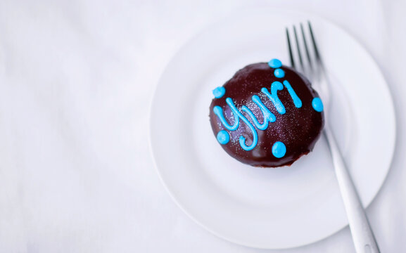 Cupcake, Chocolate Cake And Dessert On A Plate For A Birthday Celebration With A Name Or Work. Food, Unhealthy Eating And Bakery Sugar Product On A Table To Celebrate At A Party For Yuri From Above