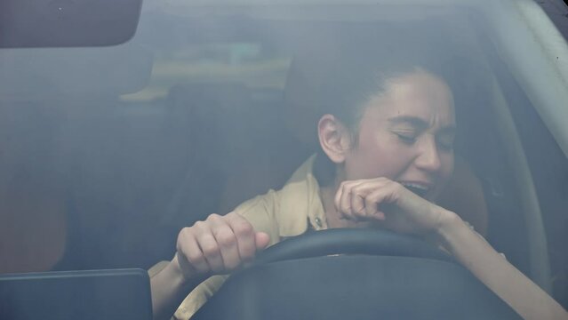 Brunette businesswoman with delighted expression sings favourite song in car. Woman listening to and singing songs in vehicle at traffic jam