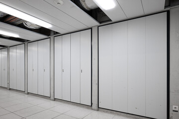 Long interior empty corridor hallway illuminated by neon lights with locker doors across both side, no people