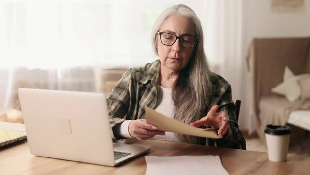 Worried gray haired senior woman open envelope and reading bad negative news feeling disappointed upset at home Defeat Loss Disappointment concept
