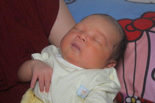 Portrait of a newborn boy who sleeps sweetly and smiles in he sleep in red clothes at a photo shoot of newborns
