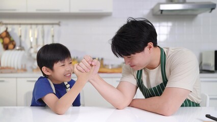Happy Asian Family Concept. Father and son playing arms wrestling and enjoying time together at home