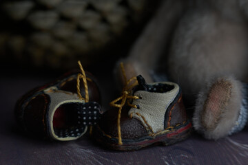 leather small shoes near the feets of teddy bear. the concept of light industry for the manufacture of stylish fashionable shoes for children with small feet and their parents