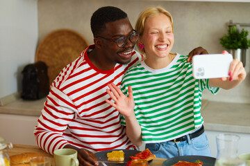 Multiracial couple taking Selfie on smart phone while enjoying breakfast  at home