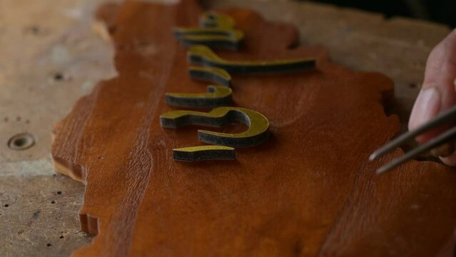 Craftsman hands accurately and precisely placing Arabic letters on wooden panel, Chaghcharan city, Afghanistan. Close-up