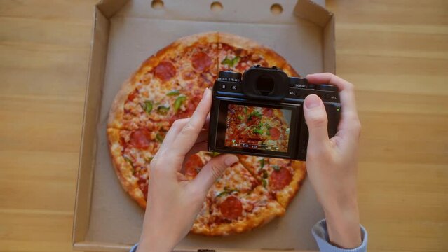 blogger takes a photo of pizza with sausage and pepper. Top view - Photographer hands use digital camera photographing appetizing fresh cooked italian. Food blog of blogging. Technology, foodporn