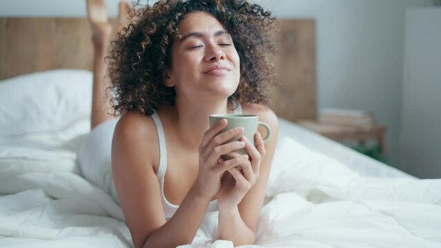 Video of  beautiful woman in underwear drinking a cup of coffee while staying on the bed. 
