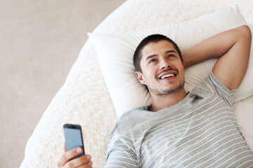 Man, happy and thinking with a phone on a bed for communication, chat or notification at home. Happy young person with a smartphone for message idea with internet connection, app and social media