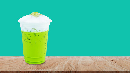Iced matcha green tea latte frappuccino with milk foam in takeaway cup on wooden table, Summer drinks with iced
