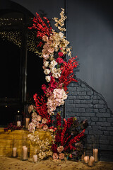 Decor with candles for surprise marriage proposal. Romantic date in restaurant. Candlelight setup decor for couple on Valentine's day. Location with arch, wall, photo zone decoration flowers. Wedding.