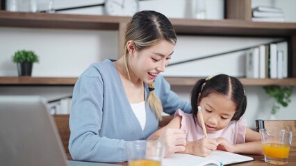 Asian mother teaching little daughter doing homework at home. Mother helping daughter doing homework. Single mother, Mother and child relationship concept